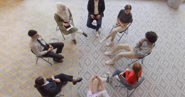 oben Aussicht von ein vielfältig Gruppe von jung Geschäft Unternehmer versammelt im ein Kreis zum ein treffen, diskutieren korporativ Herausforderungen und innovativ Lösungen innerhalb das modern Grenzen von ein groß video