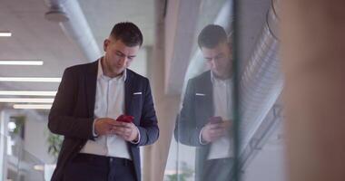 A busy businessman in a modern corporate hallway showcases his multitasking skills while using a smartphone to manage his hectic work schedule and stay connected with the fast-paced business world video