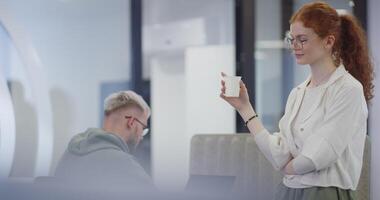 A modern businesswoman engages in a lively conversation with her colleagues while enjoying a coffee break in a contemporary office, exemplifying effective communication, teamwork, and work-life video