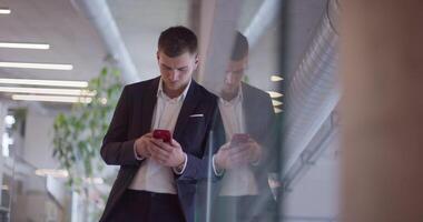 A busy businessman in a modern corporate hallway showcases his multitasking skills while using a smartphone to manage his hectic work schedule and stay connected with the fast-paced business world video