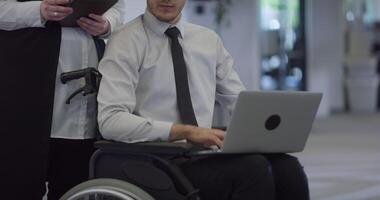 A contemplative director in a wheelchair works on a laptop in a modern office, embodying determination, professionalism, and the inclusive and accessible nature of the corporate environment. video
