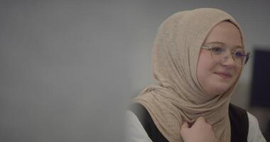 In a modern office, a Muslim entrepreneur wearing a hijab sits confidently and diligently works on her computer, embodying determination, creativity, and empowerment in the business world video