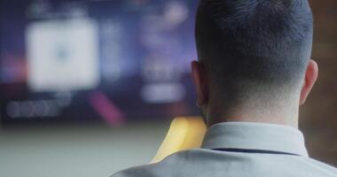 en företag företagets direktör tar en ha sönder från arbete i en modern kontor och ägnar sig åt i spel, använder sig av en joystick till spela spel på en tv, kombinerande fritid och avslappning med en rusa av kontor video