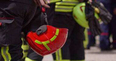A close-up perspective focuses on a firefighter's hand as they hold a safety helmet, symbolizing their preparedness and dedication to ensuring their own safety and the safety of others during video
