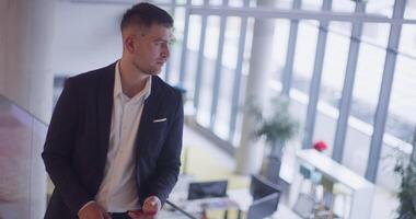 A busy businessman in a modern corporate hallway showcases his multitasking skills while using a smartphone to manage his hectic work schedule and stay connected with the fast-paced business world video