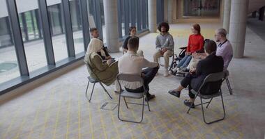 ein vielfältig Gruppe von jung Geschäft Unternehmer versammelt im ein Kreis zum ein treffen, diskutieren korporativ Herausforderungen und innovativ Lösungen innerhalb das modern Grenzen von ein groß Konzern video