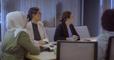 A diverse team of business experts in a modern glass office, attentively listening to a colleague's presentation, fostering collaboration and innovation. video
