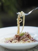 espaguetis carbonara con no fumado tocino, panceta, guanciale pesado crema, espaguetis alla carbonara comida en blanco plato en el mesa foto
