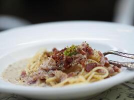 espaguetis carbonara con no fumado tocino, panceta, guanciale pesado crema, espaguetis alla carbonara comida en blanco plato en el mesa foto