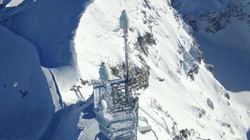Aerial view of radio antenna tower standing on high snow mountain video