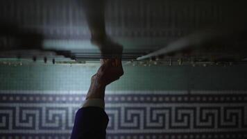 A hand is carefully selecting keys on an intricate vintage keyholder in a dark and mysterious room video