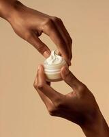 Mock Up of Hands Applying Cream from a Small Jar on Beige Background - Beauty and Cosmetics Product photo