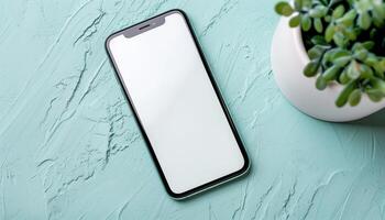 Smartphone on Turquoise Textured Surface with Potted Plant photo