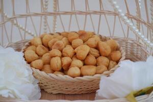 a traditional cake from Indonesia called kue sus filled with cream puffs. served on wooden basket. photo