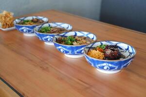 Each bowl contains different ingredients such as meats, vegetables, and rice, garnished with green herbs photo
