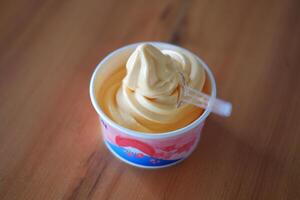 ice cream in paper cup on wood table background. soft focus. photo