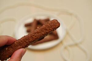Close up of a woman's hand holding a biscuit with chocolate. photo