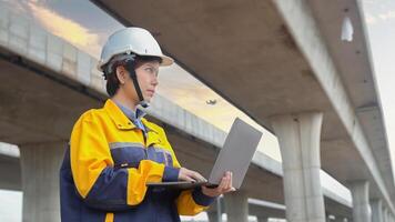 Asian female engineer uses laptop to inspect highway construction work photo