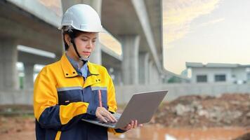 Asian female engineer uses laptop to inspect highway construction work photo