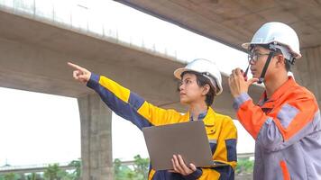 Asian male and female engineers Inspecting construction work radio command concrete road bridge highway photo
