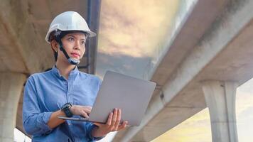 Asian female engineer uses laptop to inspect highway construction work photo