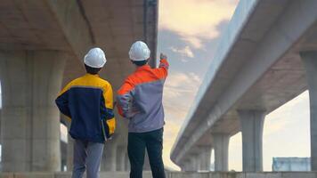 Back view of Asian male and female engineers Inspecting construction work radio command concrete road bridge highway photo