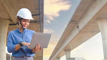 Asian female engineer uses laptop to inspect highway construction work photo