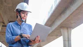 Asian female engineer uses laptop to inspect highway construction work photo