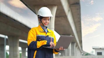 Asian female engineer uses laptop to inspect highway construction work photo