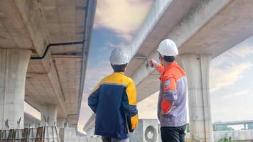 Back view of Asian male and female engineers Inspecting construction work radio command concrete road bridge highway photo