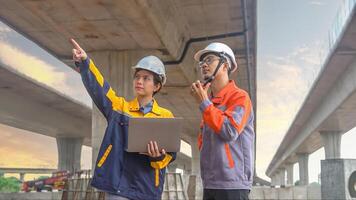 Asian male and female engineers Inspecting construction work radio command concrete road bridge highway photo