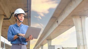Asian female engineer uses laptop to inspect highway construction work photo