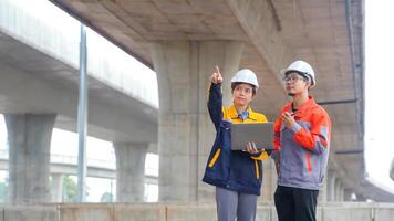 Asian male and female engineers Inspecting construction work radio command concrete road bridge highway photo
