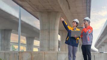 Asian male and female engineers Inspecting construction work radio command concrete road bridge highway photo