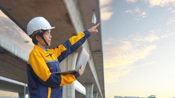 Asian female engineer uses laptop to inspect highway construction work photo