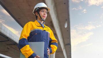 Asian female engineer holding laptop in the background, highway road photo