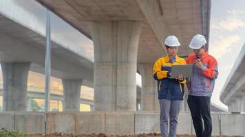 Asian male and female engineers Inspecting construction work radio command concrete road bridge highway photo