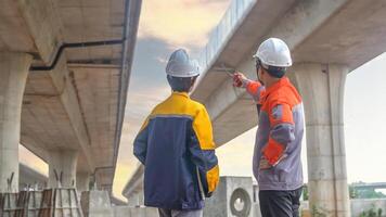 Back view of Asian male and female engineers Inspecting construction work radio command concrete road bridge highway photo