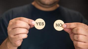 Man hand show yes or no on wood circle block. Yes No choice and decision photo