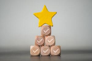 Star shape put on top of wood block with check mark, wood stack like a pyramid. Concept of excellence photo