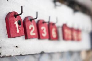 A wood red number tag for queue for motorcycle taxi drivers. Numbers for the queue photo