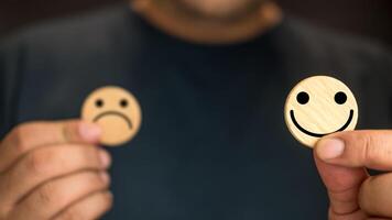 Man choice a happy smile face in wood circle block for a positive mindset selection. photo