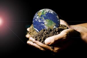 Hands Holding Earth with Soil Against Black Background Highlighting Environmental Conservation photo