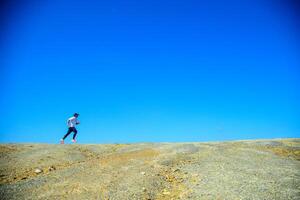 Runner on a Vast Rocky Terrain Under Clear Blue Sky, Capturing the Essence of Freedom and Adventure in Nature photo