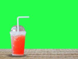 Refreshing Red Slush Drink with Straw on Woven Surface Against Green Background photo