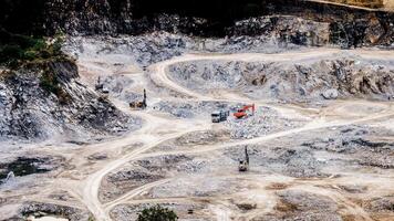 Aerial View of an Active Quarry with Heavy Machinery and Trucks on a Rocky Landscape photo