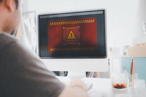 Man use computer at home with warning triangle sign for warning error Hack Alert System Warning cyber attack photo