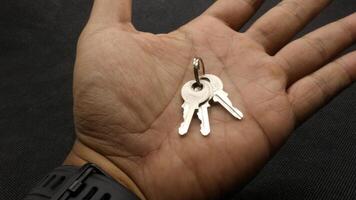 silver key with black background above the hand photo