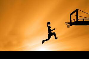 Silhouette of Basketball Player Jumping to Dunk Against Orange Sunset Sky photo