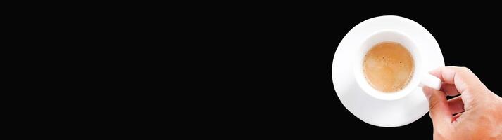 Hand Holding a Cup of Espresso Coffee Against a Black Background - Minimalist Design with Negative Space for Text or Graphics photo